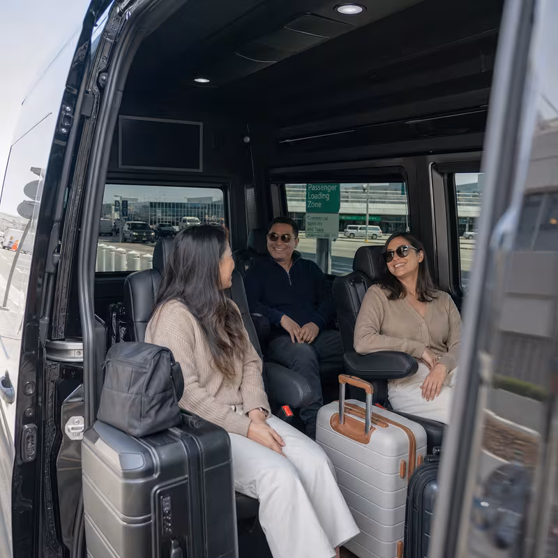 Passengers loading luggage while boarding an Oakland group shuttle