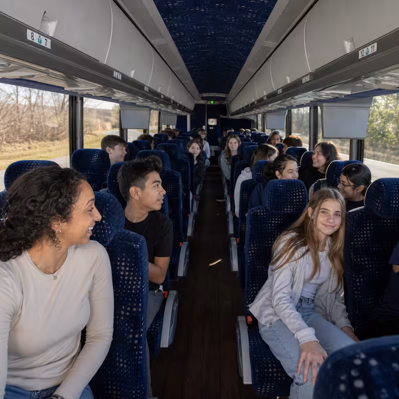 Group boarding a white charter bus for School Transportation transportation in Oakland